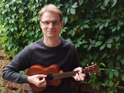 Timo-Matti Haapainen, kirkkohallituksen uskontojen kohtaamisen asiantuntija ukulele kädessään kotipihalla.