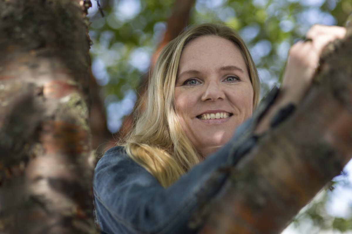 Lapsiasiavaltuutettu Elina Pekkarinen nojaa puunoksaan.