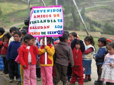 Perulaisia lapsia vastaanottamassa suomalaisryhmää. Näkyvissä kyltti, jossa toivotetaan tervetulleiksi.