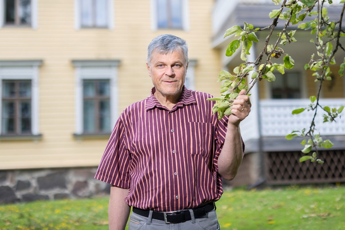 Juha Tanska Poitsilan kartanon edessä pitelee omenapuun oksaa.