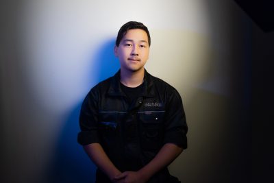 Alec Takamaa seisoo työasussaan seinää vasten.