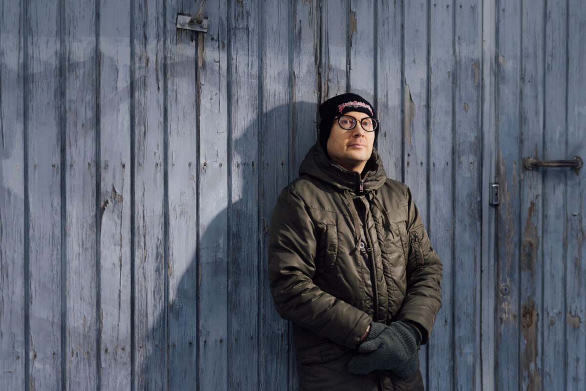 Timo Suutarinen nojaa ulkona rakennuksen seinään.