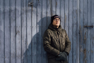 Timo Suutarinen nojaa ulkona rakennuksen seinään.